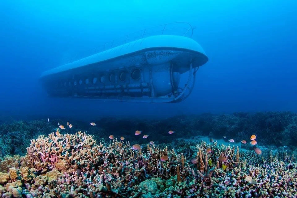 A passenger submarine cruising above a colorful coral reef with small fish